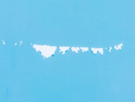 Close up to colored peeling paint texture on cement wall surface. The old cement wall, paint and putty, peels off and collapses. Grunge background texture. Paint peel off in blue color painted wall.の写真素材