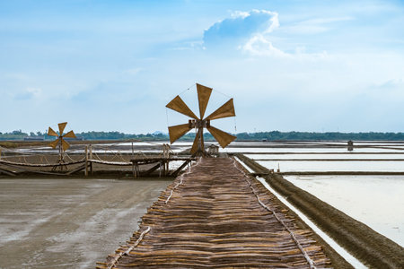 Wooden turbine at salt pan using for press seawater up to field with blue sky background in summer time of Thailand,South East Asia. Beautiful landscape of salt fields.Traditional salt farming cultureの写真素材
