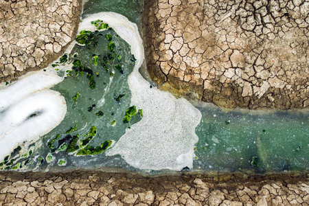 Top view of wastewater with air bubbles and moss flowing through a cracked ditch. Oxygen bubble in dirty sewage water treatment in a water filled ditch. The surface of the effluent has air bubbles.の写真素材