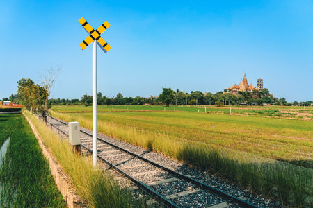 Beautiful view of the sign pole and train route through lush rice fields with Thailand's famous Wat Tham Sua and Wat Tham Khao Noi on the mountain in background. Outdoor tourism with beautiful nature.の写真素材
