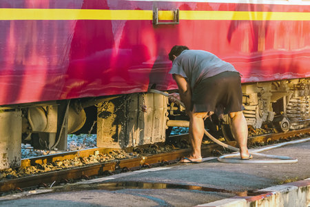 Male janitor clean and wash exterior of train. Worker cleaning the train on railways at train station before the scheduled departure. Cleaning staff clean washing train for tourist travel holidays.の写真素材