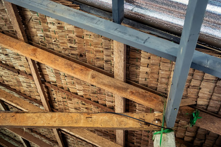 Thatched roof with ceiling covered with insulation combined. Aluminum foil installed under roof for...