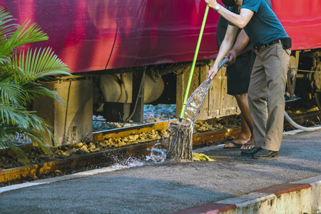 Male janitor clean and wash exterior of train. Worker cleaning the train on railways at train station before the scheduled departure. Cleaning staff clean washing train for tourist travel holidays.の写真素材