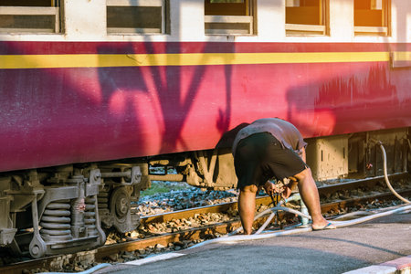 Male janitor clean and wash exterior of train. Worker cleaning the train on railways at train station before the scheduled departure. Cleaning staff clean washing train for tourist travel holidays.の写真素材