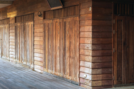 Traditional antique wooden folding door Asian style frame. Thai traditional wooden gate of historical architecture. Beautiful retro wooden folding door with lock under evening sunlight. Vintage Door.の写真素材