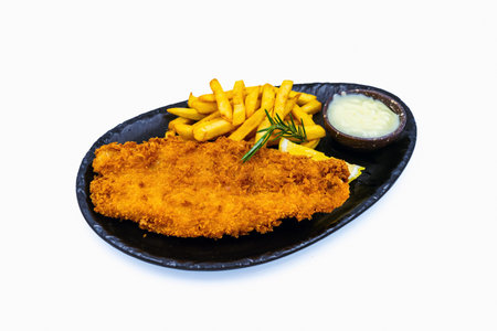 A delicious fried meat steak with cheese,french fries, with mayonnaise on plate with white background. Homemade dish,fried dolly fish steak. Fried fish and French Fries Serving Plate Fast Food Meals.の写真素材