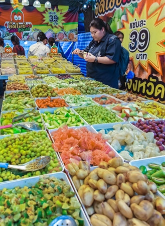 NAKHON PATHOM, THAILAND - NOVEMBER 23,2023 : Unidentified young women choose to buy various kinds of fruits and pickled fruits, which are popularly eaten by the majority of Thai women at local market.のeditorial素材