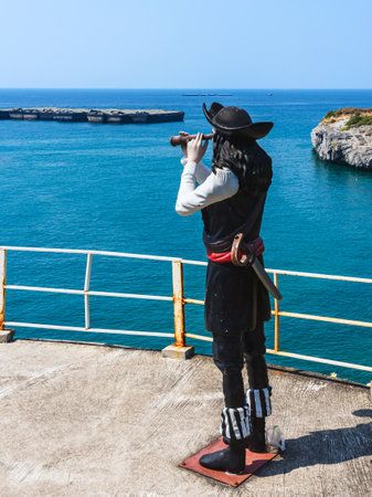 CHONBURI-THAILAND,JANUARY 21, 2024 : A pirate statue using binoculars on the hillside shore with beautiful scenic at Koh Sichang. The figure of pirate on sea background. Sculpture of a sea captain.のeditorial素材
