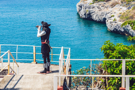 CHONBURI-THAILAND,JANUARY 21, 2024 : A pirate statue using binoculars on the hillside shore with beautiful scenic at Koh Sichang. The figure of pirate on sea background. Sculpture of a sea captain.のeditorial素材