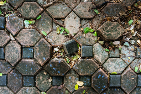 Pavement surface is damaged and dangerous. Broken brick blocks can pose danger to pedestrians. Old hexagonal brick blocks that collapse to create different level floor. Damaged and dirty brick blocks.の写真素材