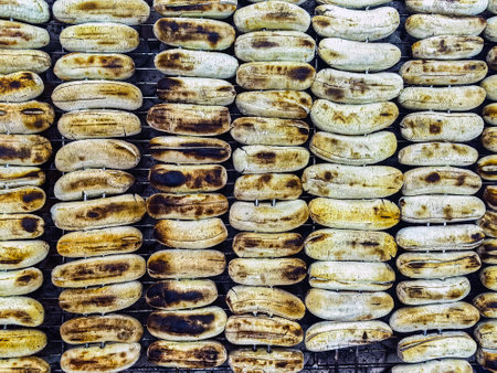 Grilled bananas on skewers on hot charcoal stove, grilled in traditional Thai style Thai street food Thai snacks. Banana Roasted on iron net with hot charcoal stove at Street Food. Grilled Bananas.の写真素材