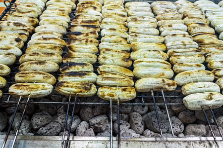 Grilled bananas on skewers on hot charcoal stove, grilled in traditional Thai style Thai street food Thai snacks. Banana Roasted on iron net with hot charcoal stove at Street Food. Grilled Bananas.の写真素材