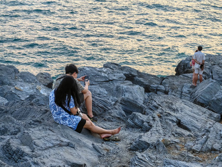 Happy tourists in casual clothes relaxing and enjoying valley view before sunset near the calm sea.  Happiness people on top of mountain enjoying view coast. Freedom and active lifestyle concept.の写真素材
