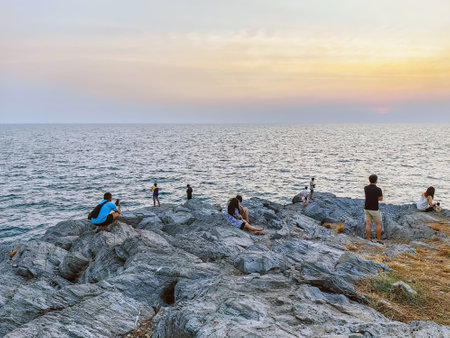 Happy tourists in casual clothes relaxing and enjoying valley view before sunset near the calm sea.  Happiness people on top of mountain enjoying view coast. Freedom and active lifestyle concept.の写真素材