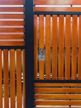 Broken shera wood board fence. Hole in wooden wall. Damaged weathered brown picket fence with broken rails and planks. A broken plank on the fence. Wooden wall with broken boards. Broken fence.の写真素材
