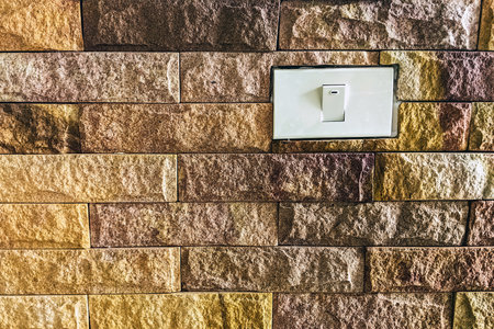 Light switch on horizontal modern brick wall for pattern and background. Stone natural abstract background textured. White light on-off switch installed on stone wall background in horizontal pattern.の写真素材