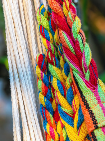 Colorful cotton rope. Thick cotton rope showing detail of threads and fibres. Yarn braid rope of cradle. Multicolored yarn has been braided into a braid. Knitted fabric background. Selective focus.の写真素材