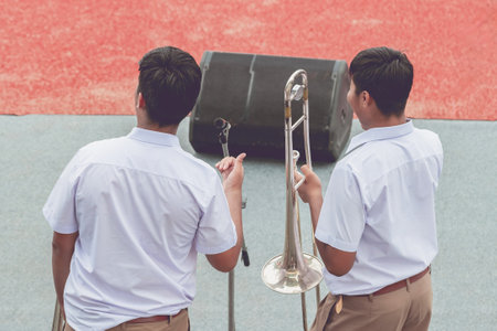 Group of Asian students in uniform perform a orchestra band in festival performance at stadium. Students play marching band in celebrations. Students Music band playing Jazz Music. Education outdoors.の写真素材