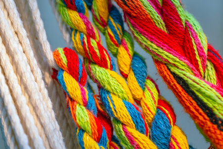 Colorful cotton rope. Thick cotton rope showing detail of threads and fibres. Yarn braid rope of cradle. Multicolored yarn has been braided into a braid. Knitted fabric background. Selective focus.の写真素材