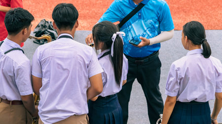 Group of Asian students in uniform perform a orchestra band in festival performance at stadium. Students play marching band in celebrations. Students Music band playing Jazz Music. Education outdoors.の写真素材