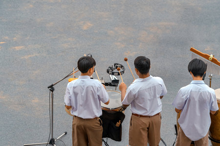 Group of Asian students in uniform perform a orchestra band in festival performance at stadium. Students play marching band in celebrations. Students Music band playing Jazz Music. Education outdoors.の写真素材
