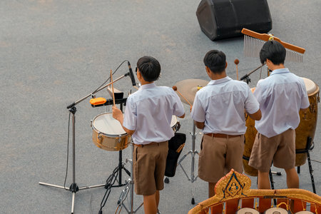 Group of Asian students in uniform perform a orchestra band in festival performance at stadium. Students play marching band in celebrations. Students Music band playing Jazz Music. Education outdoors.の写真素材