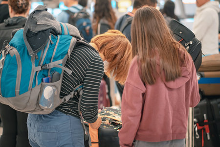 People standing with luggage in queue to check in in airport terminal. Tourists waiting in line at check-in area. Passengers queuing up to check in for their flights in go to travel visit journey.の写真素材