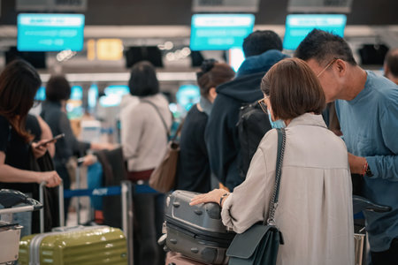 People standing with luggage in queue to check in in airport terminal. Tourists waiting in line at check-in area. Passengers queuing up to check in for their flights in go to travel visit journey.の写真素材