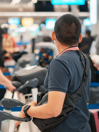 People standing with luggage in queue to check in in airport terminal. Tourists waiting in line at...