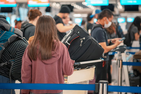 People standing with luggage in queue to check in in airport terminal. Tourists waiting in line at check-in area. Passengers queuing up to check in for their flights in go to travel visit journey.の写真素材