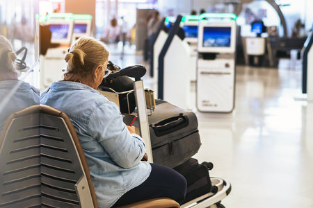 Elderly woman using smartphone sit on seat waiting to check in at airport. Tourist senior woman sit on bench in airport hall in waiting for flight. Senior woman waiting to board at airport terminal.の写真素材