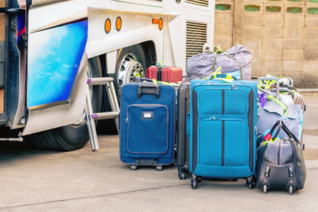 Many bag and luggage for loading into under vehicle or bus to prepare for trip in front of hotel. Several suitcases waiting for luggage pick-up bus to be taken. Selective focus. Trip or Tour concept.の写真素材