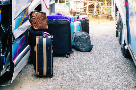 Many bag and luggage for loading into under vehicle or bus to prepare for trip in front of hotel. Several suitcases waiting for luggage pick-up bus to be taken. Selective focus. Trip or Tour concept.の写真素材