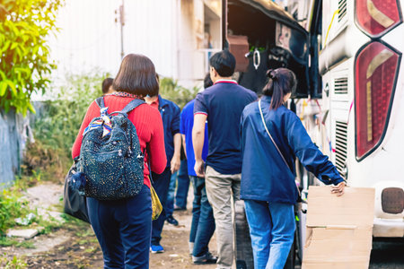 Tourists putting travel bag into travel bus at city street. Bus passengers putting luggage into the trunk when the bus stopped at terminal. Pack luggage and board the sightseeing bus. Happy journey.の写真素材