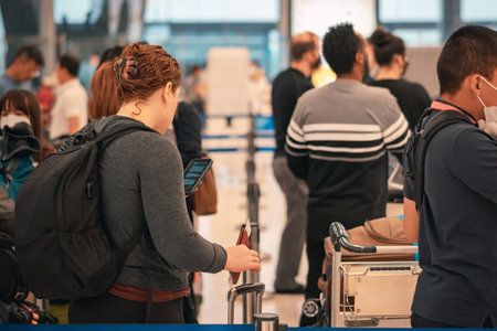 People standing with luggage in queue to check in in airport terminal. Tourists waiting in line at check-in area. Passengers queuing up to check in for their flights in go to travel visit journey.の写真素材