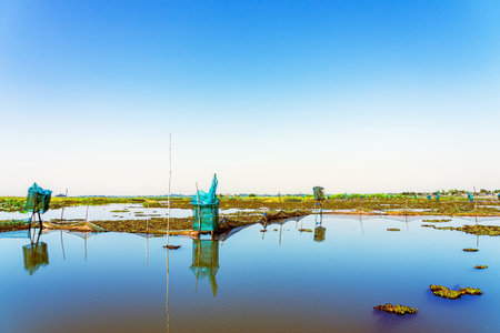 Traditional fish trap with beautiful landscape view. Shrimp and crab traps. Fish trapping on river. Nature fishery background. Dip catcher fishing net homemade of blue nylon nets and steel frame.の写真素材