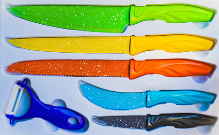 Top view of various types and colors of kitchen knives in a white knife box. Different types of knives with different colors for use in cutting and cooking in the kitchen. Set of knives in white box.の写真素材