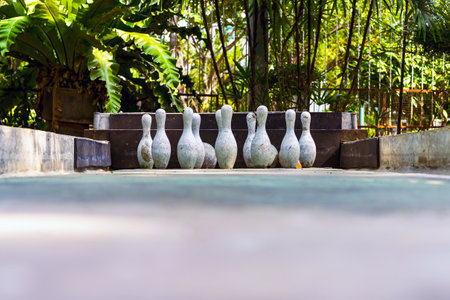 Cement toy bowling with skittles for decoration on lawn games in garden or yard. Outdoor bowling alley with bowling balls and pins made of decorative concrete for relaxing in park. Selective focus.の写真素材