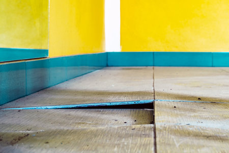 Background with falling off tiled tiles in living room. Close up of cracked ceramic tiles on a...
