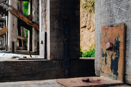 The ancient railway piers and large beams made of wood support an old rundown train bridge and were...