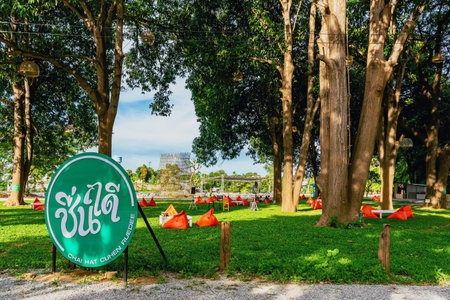 KANCHANABURI, THAILAND - JULY 13, 2020 : View of orange triangle bean bags and cushions with white wooden table for customers to relax outdoors on green grass under shade of tree at Had Chuen Ruedee.のeditorial素材