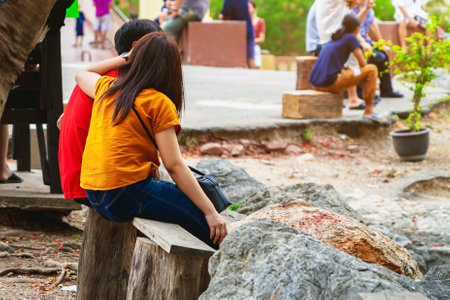 Young couple relaxing and flirts on wooden bench. Sweet lovers relax with beautiful outdoor natural. Lovely young couple sharing moments of bliss by sitting together. Relax with beautiful outdoor.の写真素材