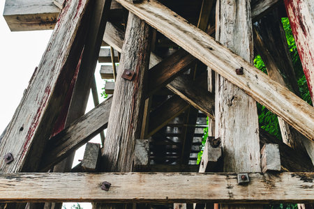 The ancient railway piers and large beams made of wood support an old rundown train bridge and were constructed during World War II.  View of old wooden bridge of train railway along cliffs and riversの写真素材