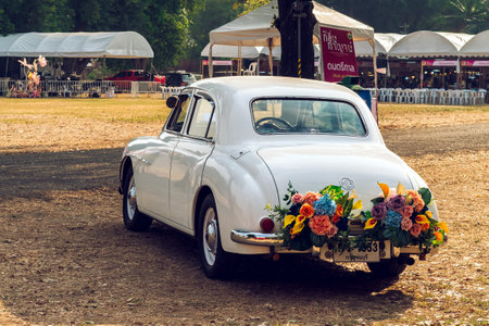 KANCHANABURI,THAILAND-FEBRUARY 12,2024 : An exhibition of beautiful antique cars decorated with artificial flower bouquets on 
lawn at The old paper mill. Vintage car with beautiful flower bouquet.のeditorial素材