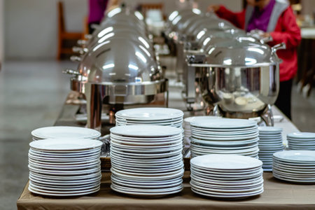 Stalks of plain white plates on top of buffet table. Stack of white ceramic dish ready for party. Dishware on table for buffet. Many white plates stacked together in restaurant.  Selective focus.の写真素材