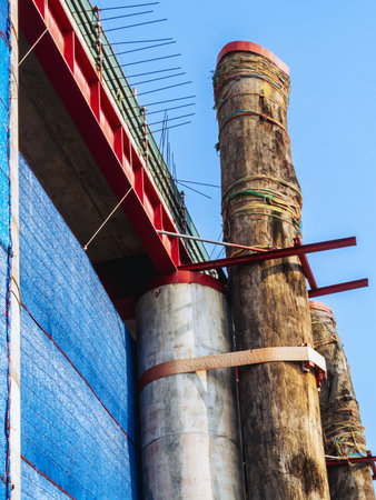 Large wooden posts attached to concrete posts to support the strength of construction. Appearance of supporting timber and concrete pillars holding up of building. Wooden support on concrete pillars.の写真素材