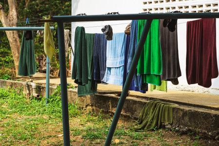 Towels hanging laundry on washing line at backyard. Clothesline with fresh washed towels outdoors at home. Fresh clean towel drying on washing line. Laundry hung on clothesline made of stretched wireの写真素材