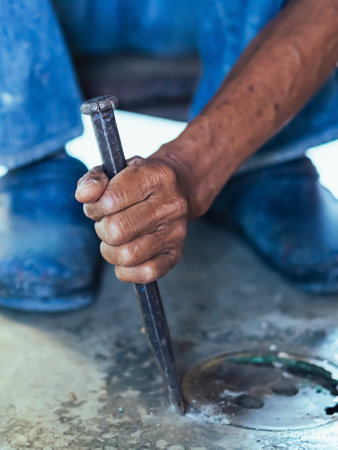Elderly worker of water utility maintenance service change sewer manholes in house. Hands of old man changing and repairing brass sewer cover of sewerage system. Maintenance of toilet drainage system.の写真素材