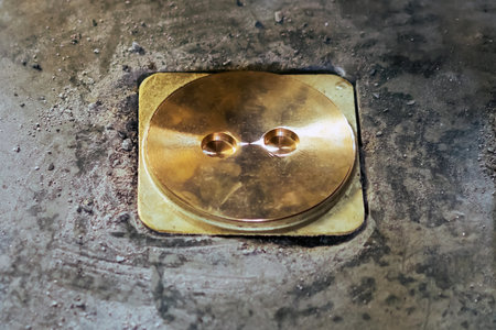 New brass cover tank Installed on concrete floor. New Brass drain lid or  circular metal manhole cover for sealing on the top set into a concrete surface.  Maintenance of toilet drainage system.の写真素材