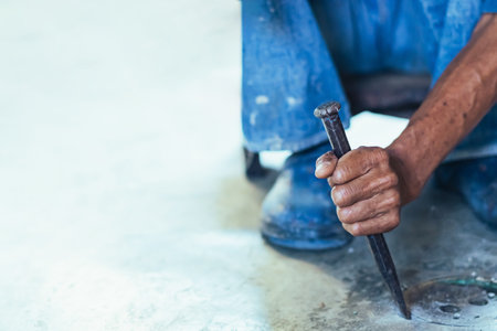 Elderly worker of water utility maintenance service change sewer manholes in house. Hands of old man changing and repairing brass sewer cover of sewerage system. Maintenance of toilet drainage system.の写真素材